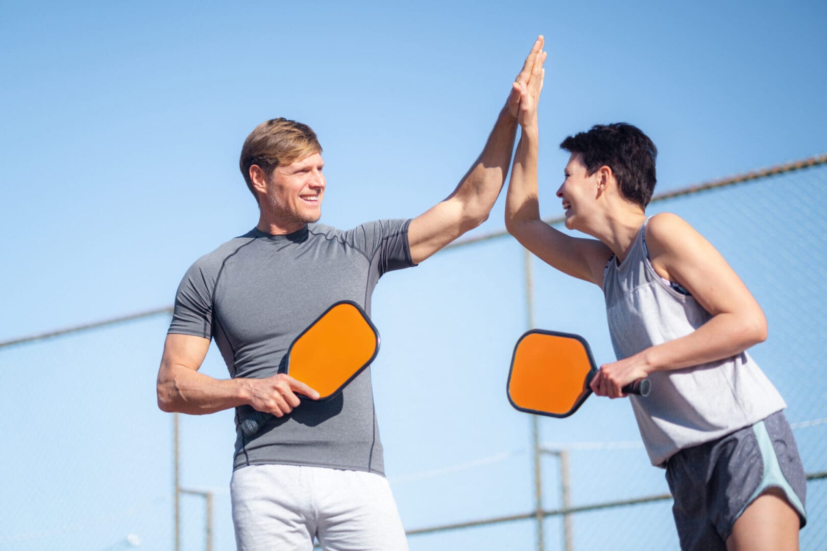 Two people high-fiving on pickleball court.