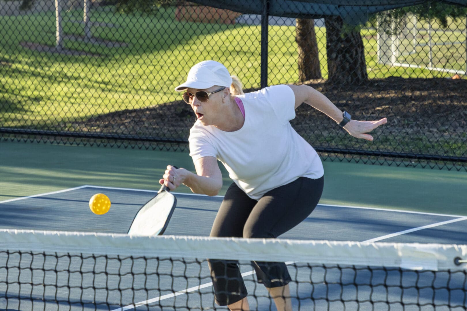 Woman playing pickleball on outdoor court.