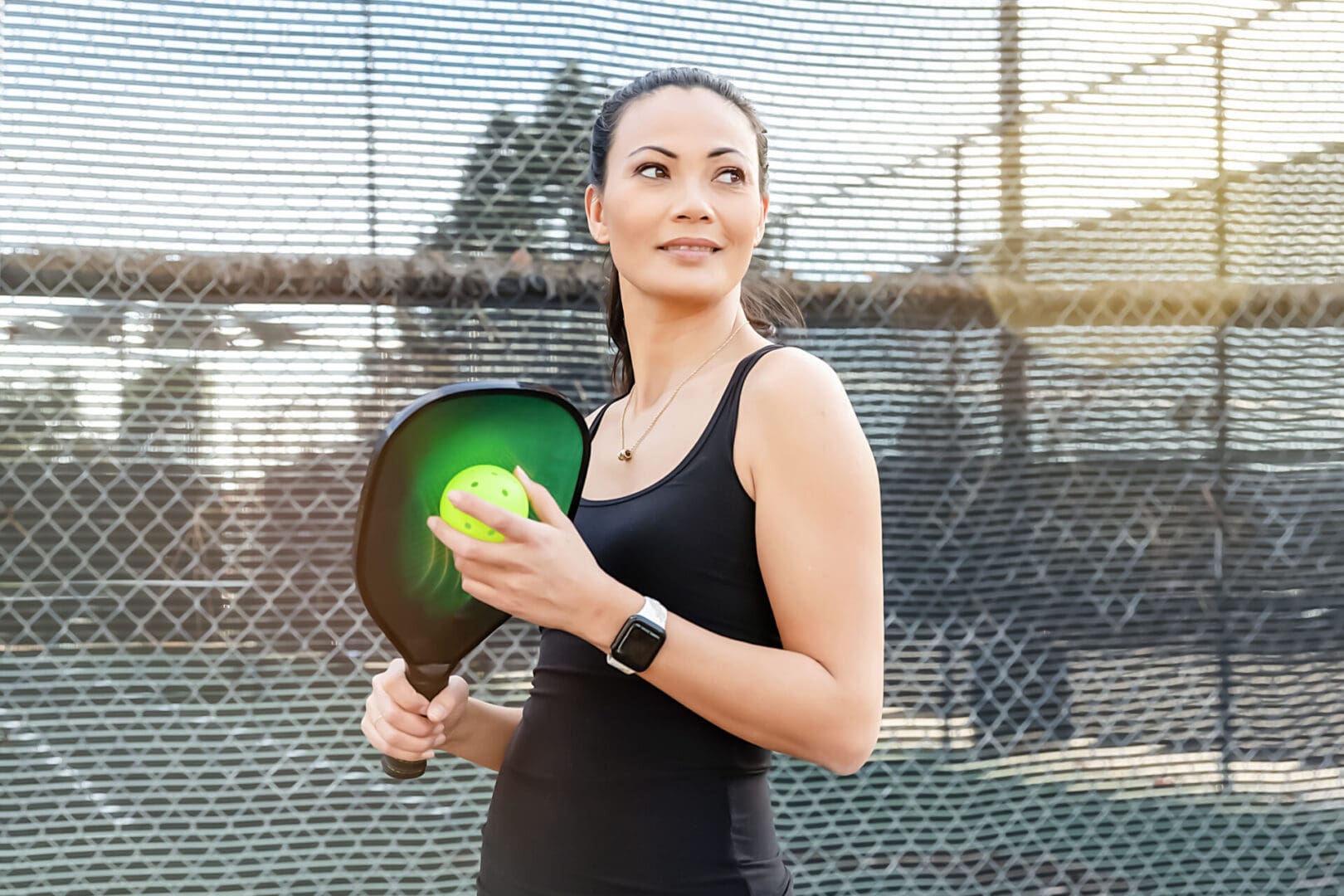 Woman holding pickleball paddle and ball.